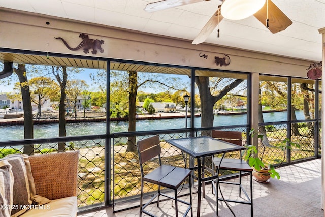 sunroom featuring a water view and a ceiling fan