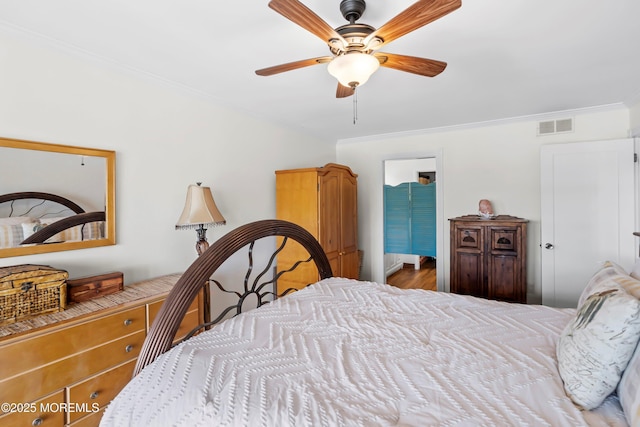 bedroom with ornamental molding, a ceiling fan, wood finished floors, and visible vents
