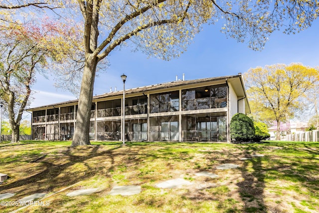 back of property with fence and a sunroom
