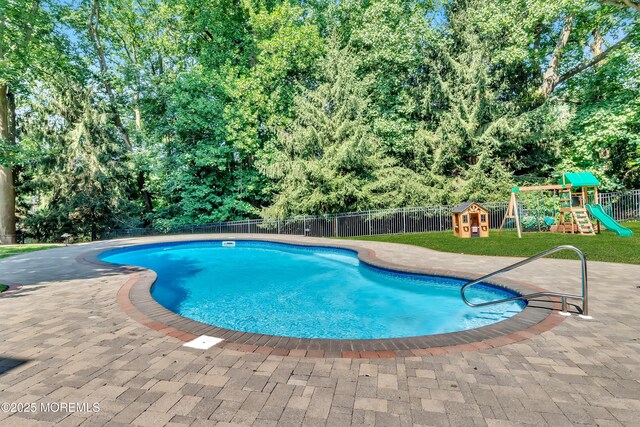 view of swimming pool featuring a patio, fence, a playground, and a fenced in pool