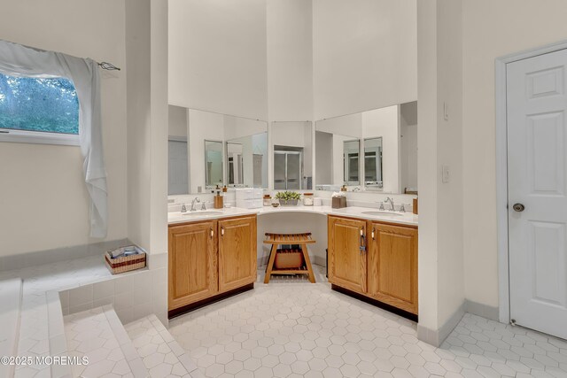 full bath featuring double vanity, a sink, and a towering ceiling