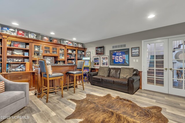 living room featuring recessed lighting, visible vents, french doors, and light wood-type flooring