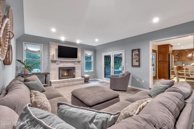 living room with light wood-style floors, baseboards, a fireplace, and recessed lighting
