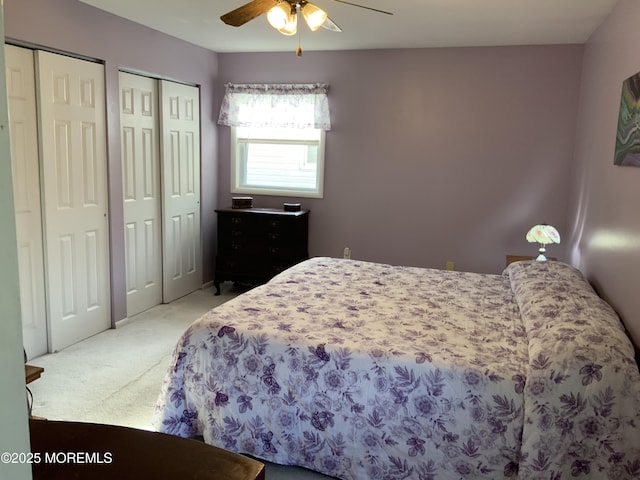bedroom featuring two closets, a ceiling fan, and carpet