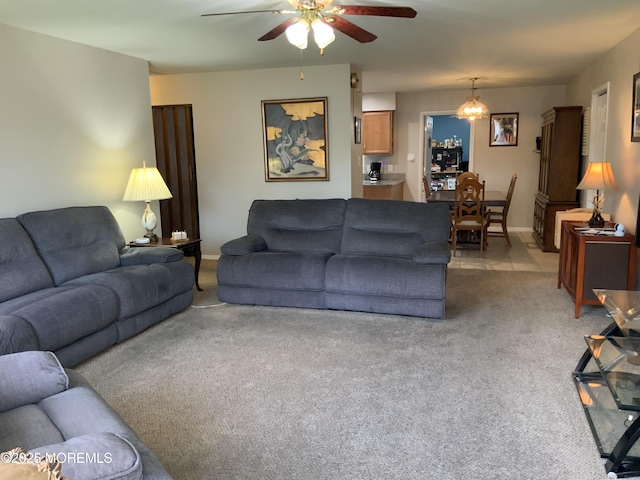 living room featuring a ceiling fan, baseboards, light carpet, and light tile patterned floors