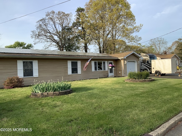 single story home with an attached garage, solar panels, and a front lawn