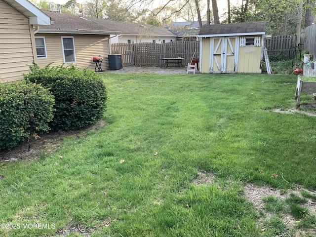 view of yard with an outdoor structure, a fenced backyard, central AC, and a shed