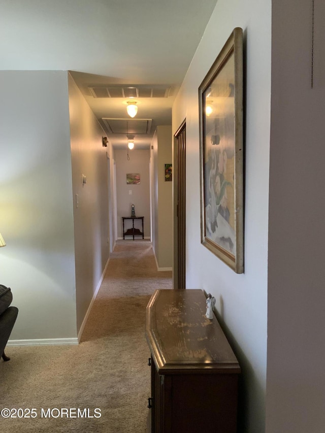 hallway with carpet floors, baseboards, visible vents, and attic access