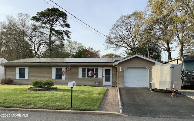 single story home featuring an attached garage, solar panels, a front yard, and aphalt driveway