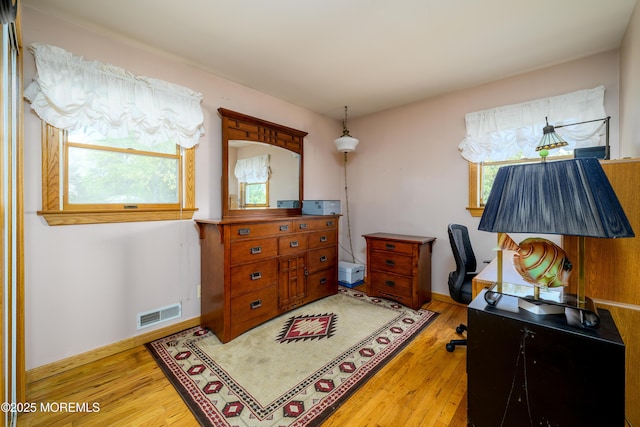 office space with baseboards, wood finished floors, and visible vents