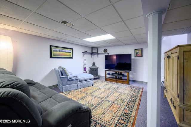 living room with visible vents, a wood stove, baseboards, a paneled ceiling, and carpet flooring