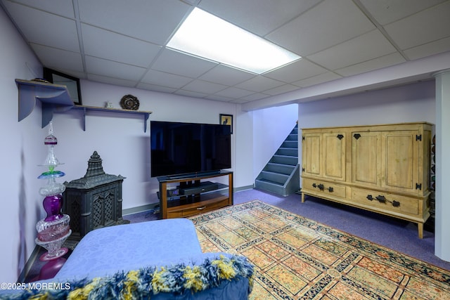 living room featuring baseboards, carpet flooring, a paneled ceiling, and stairway