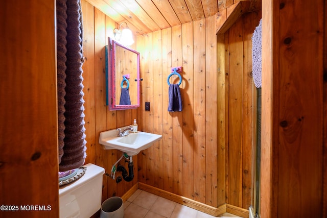 bathroom featuring toilet, tile patterned floors, wood walls, baseboards, and wood ceiling
