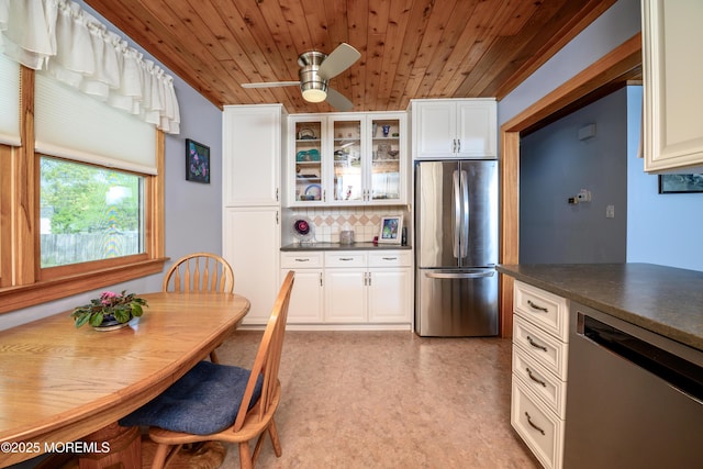 kitchen featuring wood ceiling, decorative backsplash, dark countertops, appliances with stainless steel finishes, and glass insert cabinets