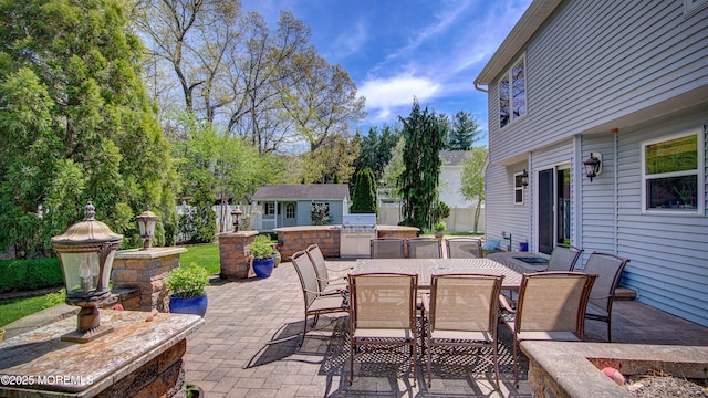 view of patio / terrace featuring fence, an outbuilding, outdoor dining area, and an outdoor kitchen
