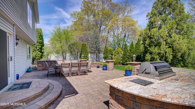 view of patio with an outdoor kitchen, fence, and outdoor dining area
