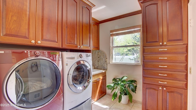 clothes washing area featuring ornamental molding, cabinet space, light tile patterned floors, and washer and dryer