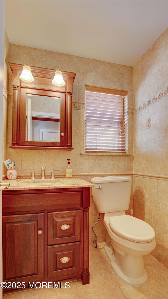 bathroom featuring tile patterned floors, vanity, toilet, and tile walls