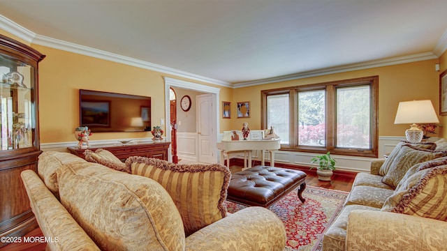 living room with crown molding, a wainscoted wall, and wood finished floors