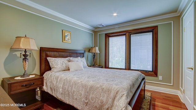 bedroom with visible vents, ornamental molding, baseboards, and wood finished floors