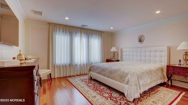 bedroom featuring crown molding, visible vents, and light wood-style flooring