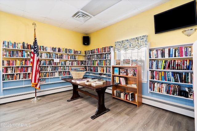 82 Fox Glove, Toms River, NJ 08755 - sitting room with wood finished floors, a baseboard heating unit, visible vents, wall of books, and a paneled ceiling