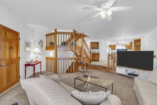 living room with stairway, light colored carpet, and ceiling fan with notable chandelier