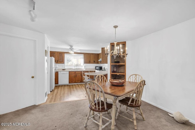 dining area featuring ceiling fan with notable chandelier and light colored carpet