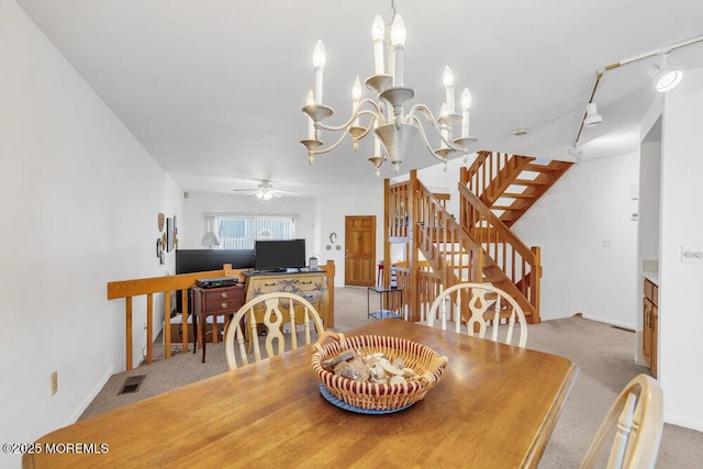 carpeted dining area with stairs, visible vents, and ceiling fan with notable chandelier