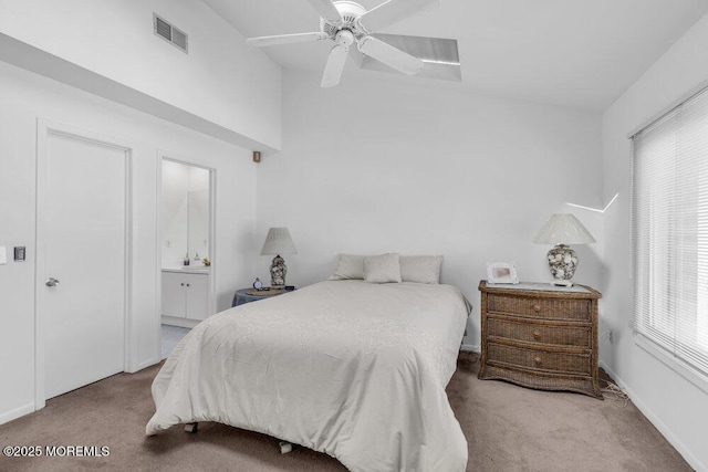 carpeted bedroom featuring visible vents, a ceiling fan, ensuite bath, and vaulted ceiling
