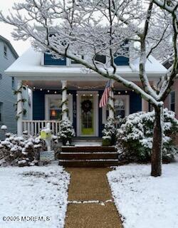 snow covered property entrance featuring covered porch