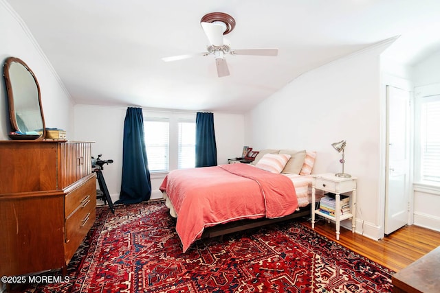 bedroom featuring crown molding, ceiling fan, baseboards, wood finished floors, and vaulted ceiling