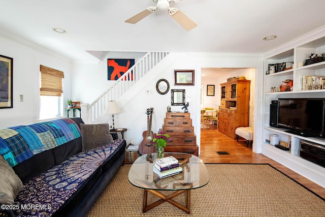 living room with crown molding, stairway, a ceiling fan, and wood finished floors