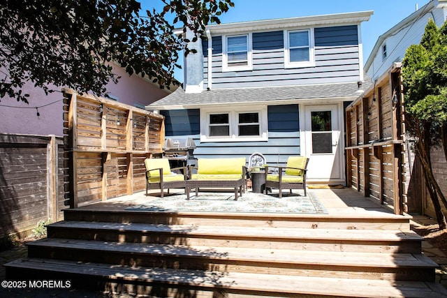rear view of property with outdoor lounge area, roof with shingles, fence, and a deck