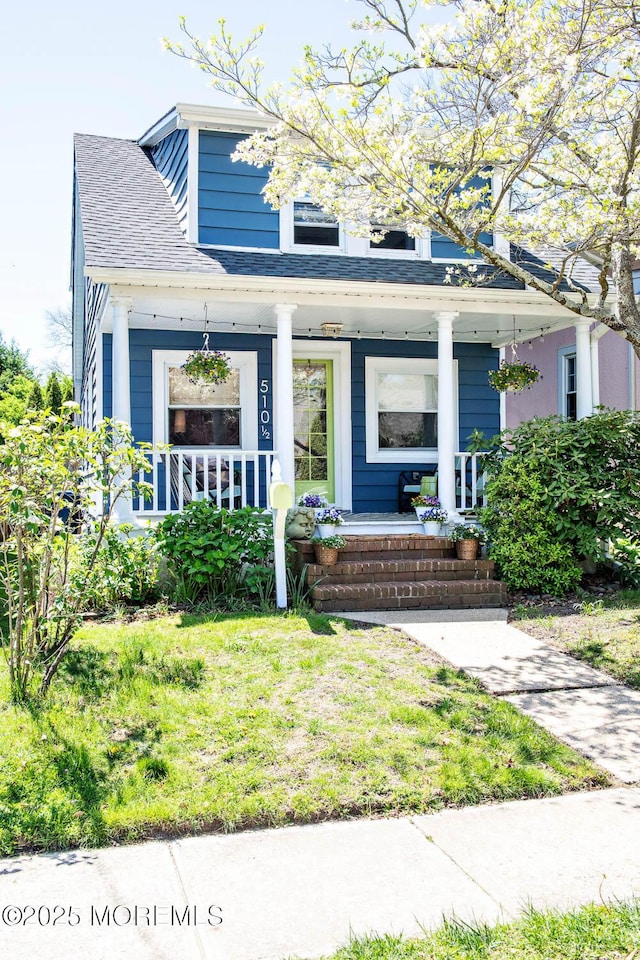 bungalow-style home featuring a porch, a shingled roof, and a front yard