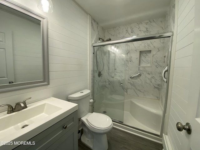 full bath with wooden walls, a marble finish shower, vanity, and toilet
