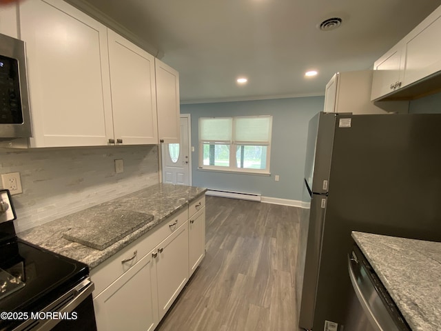 kitchen with visible vents, stainless steel appliances, white cabinetry, backsplash, and a baseboard heating unit