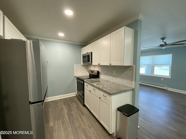 kitchen with baseboards, stone countertops, baseboard heating, backsplash, and stainless steel appliances