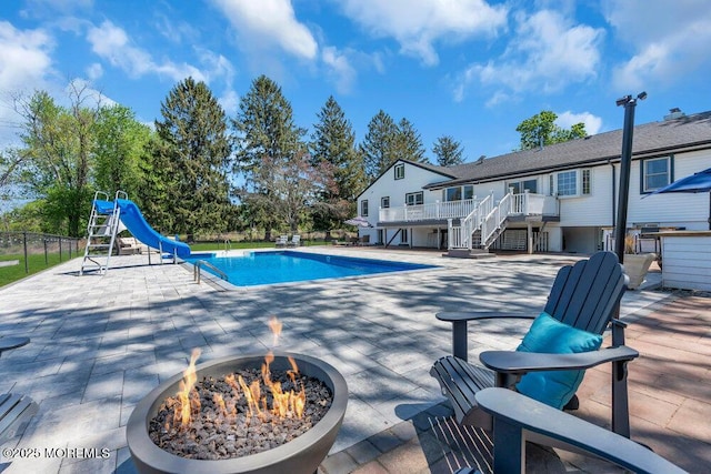 115 Phalanx Rd, Colts Neck, NJ 07722 - view of swimming pool with a wooden deck, stairs, a fenced in pool, an outdoor fire pit, and a water slide