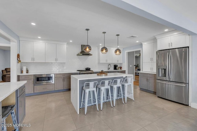 115 Phalanx Rd, Colts Neck, NJ 07722 - kitchen with visible vents, a breakfast bar, wall chimney range hood, tasteful backsplash, and appliances with stainless steel finishes