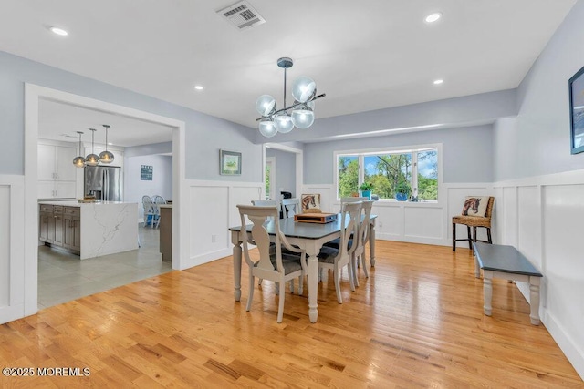 115 Phalanx Rd, Colts Neck, NJ 07722 - dining area featuring visible vents, wainscoting, a chandelier, a decorative wall, and light wood-style flooring
