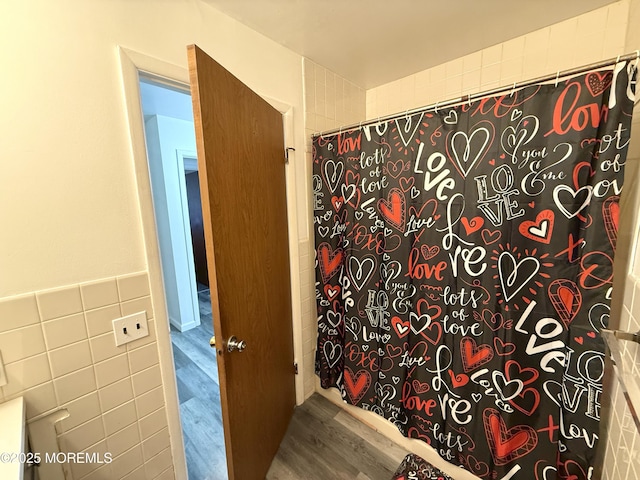 bathroom featuring tile walls, wood finished floors, and a shower with shower curtain