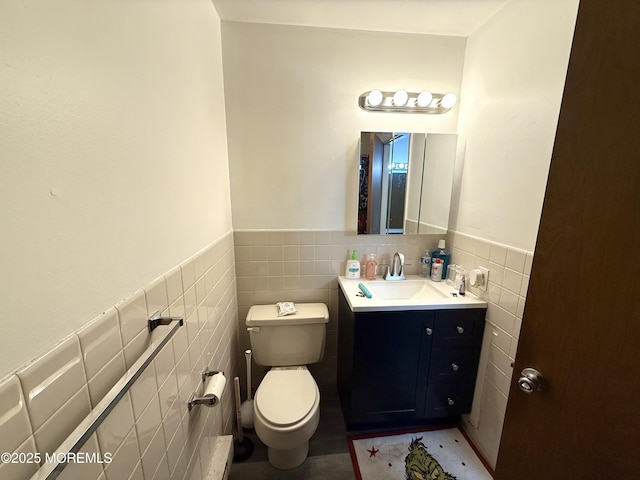 bathroom with vanity, wainscoting, toilet, and tile walls