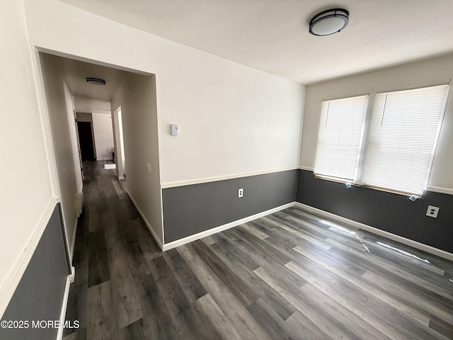 spare room featuring dark wood-type flooring and baseboards