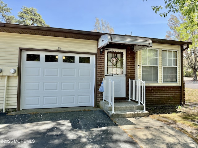 view of front facade with an attached garage, aphalt driveway, and brick siding