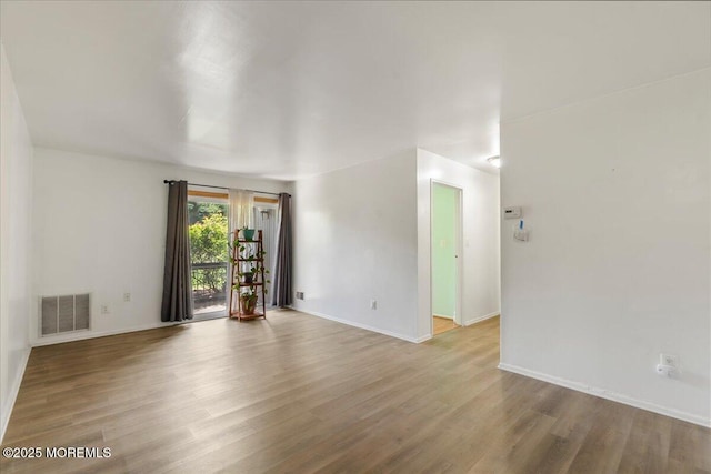spare room with visible vents, wood finished floors, and baseboards