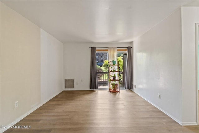 unfurnished room with baseboards, visible vents, and wood finished floors