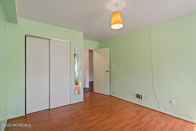 unfurnished bedroom featuring a closet, visible vents, and wood finished floors
