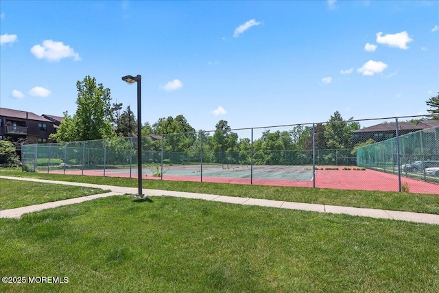 view of sport court featuring fence and a lawn
