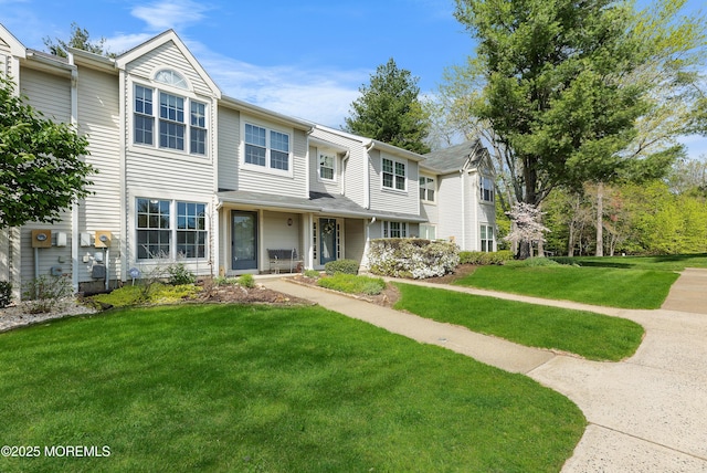 townhome / multi-family property featuring covered porch and a front yard